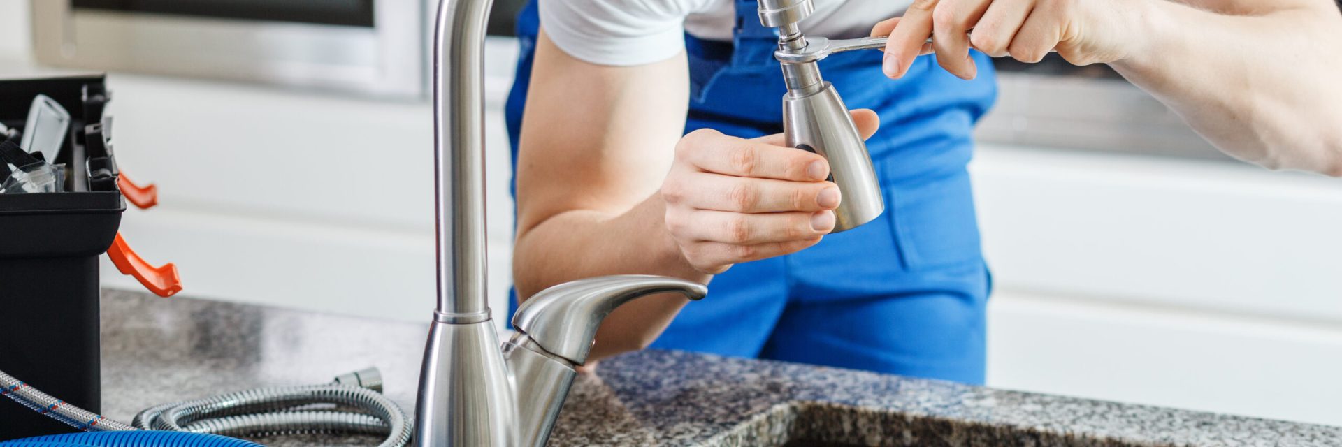 Smiling plumber fixing faucet