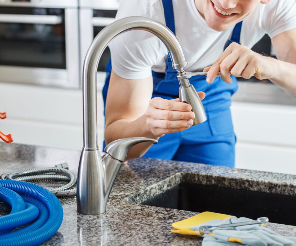 Smiling plumber fixing faucet