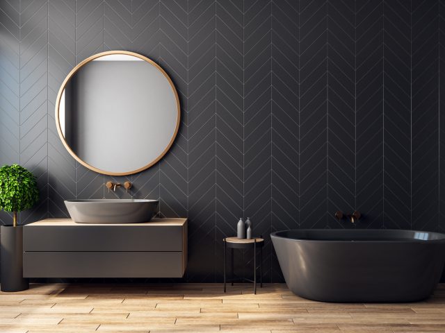 Modern black bathroom interior with decorative tree, bath tub, sink, round mirror, sunlight and copy space. 3D Rendering