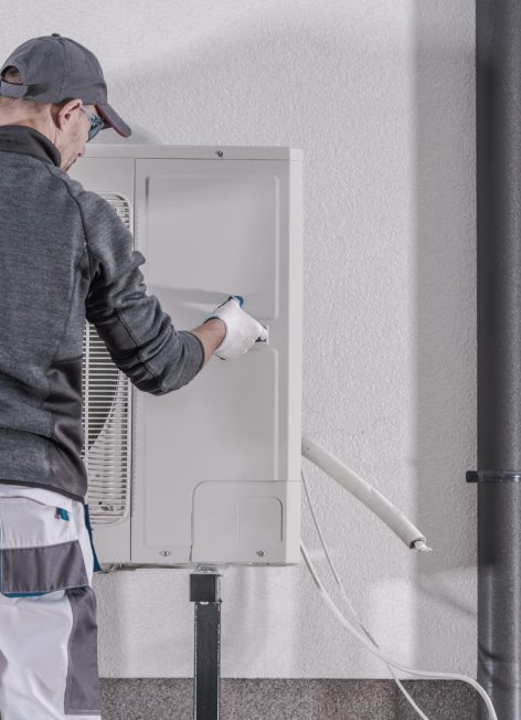 Heat Pump Replacing by Professional Caucasian Heating Technician. Industrial Theme.