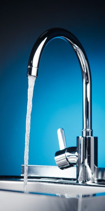 mixer tap with flowing water, blue background